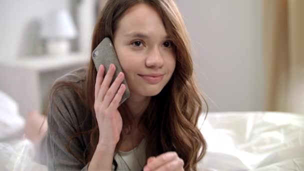 Mujer joven hablando por teléfono móvil en la cama. Mujer sonriente hablando por teléfono — Vídeos de Stock