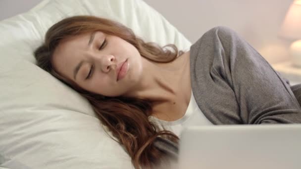 Unavená žena pracující na přenosném počítači v ložnici. Smutná žena probudí v posteli — Stock video