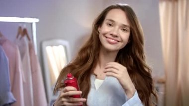 Neşeli kadın saç sprey uygulayarak. Kadın saç moda