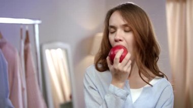 Evde kırmızı elma yiyen neşeli kadının portresi. Sağlıklı kadın meyve yeme