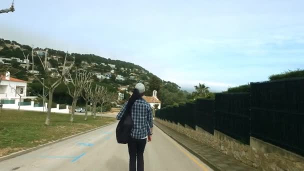 Um tipo a andar na estrada com um saco de guitarra. Voltar vista músico menino viajando — Vídeo de Stock