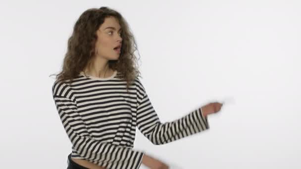 Молода жінка рекламний продукт з ручним жестом на білому тлі — стокове відео