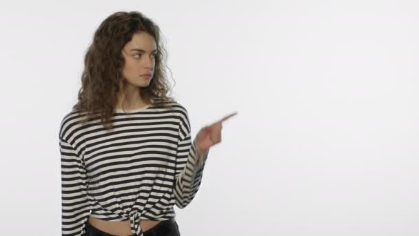 Молодая женщина показывает пальцем пространство для копирования. Довольная женщина рекомендует продукт — стоковое видео
