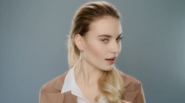 Şehvetli iş kadını kameraya bakıyor. Gri üzerinde genç kadın portresi