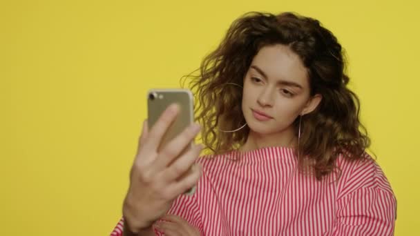 Mujer joven haciendo foto selfie en el teléfono móvil sobre fondo amarillo — Vídeo de stock