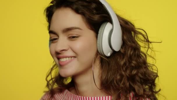 Une jeune femme écoute de la musique dans un casque. Fille heureuse dans casque sur jaune — Video