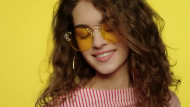Fashion woman in sun glasses on yellow. Portrait of young woman dancing — Stock Video