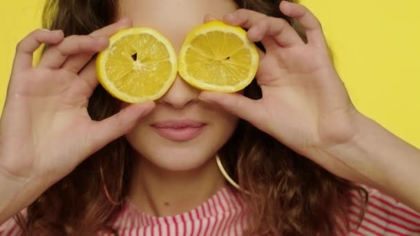 Jeune femme embrassant les lèvres avec des tranches de citron devant les yeux — Video