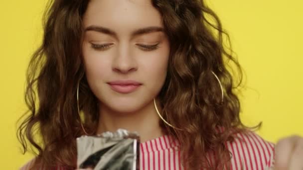 Молода жінка відкриває шоколадний батончик. Портрет щасливої дівчини, що їсть шоколад — стокове відео