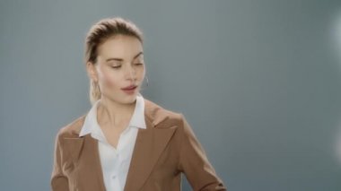 Gri arka planda ürünü sunan genç bir iş kadını