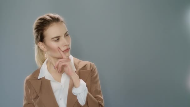 Задумчивая деловая женщина смотрит на продукт на сером фоне — стоковое видео