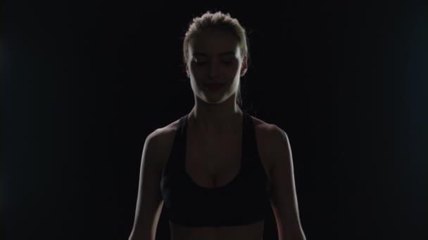 Fit Frau posiert mit Hanteln in den Händen auf schwarzem Hintergrund. Sportlerin — Stockvideo