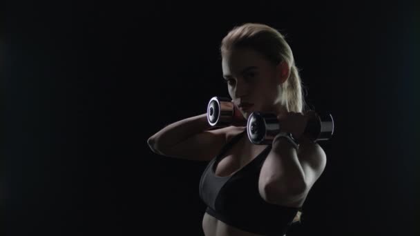 Fit girl pozowanie z hantlami na ramionach w studio. Sport kobieta sylwetka — Wideo stockowe