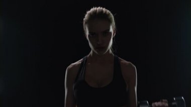 Ağırdan alan halterli, formda kadın eğitimi. Güçlü kız dambılları kaldırıyor.