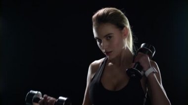 Spor salonundaki kadın siyah arka planda halter egzersizi yapıyor. Spor modeli