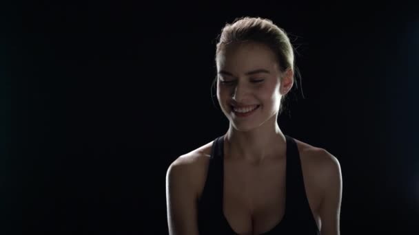 Sportovní žena s ručníkem na ramenou pózovat na černém pozadí. Fitness model — Stock video