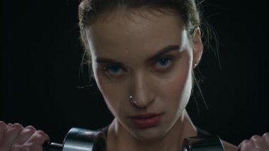 Spor kadın suratı. Formda bir kızın siyah arka planda dambılı kaldırması..