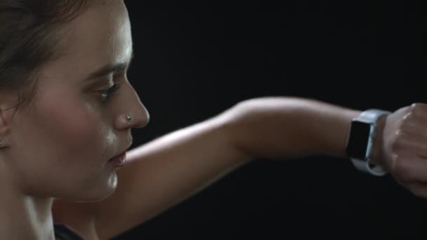 Spor kadını siyah arkaplanda akıllı saat ekranına dokunuyor — Stok video