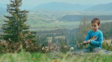 Küçük çocuk, şenlik ateşinde domuz yağı ızgara yapıyor. Çocuk kamp şömine yemek yemek