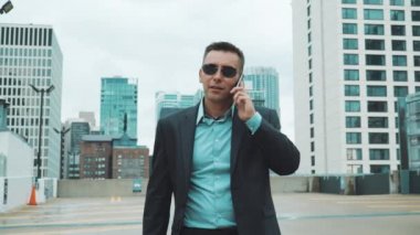 Takım elbiseli Genç adam şehirde telefonda konuşuyor. Takım elbiseli yakışıklı işadamı
