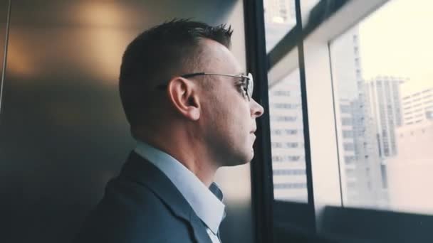 Modern man descending by elevator with transparent walls. Business man in lift — Stock Video