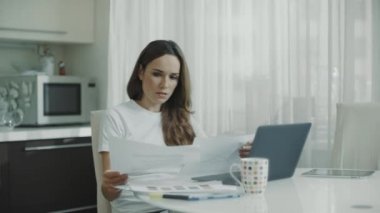 Ev işyerinde finansal veri çizelgelerini analiz eden iş kadını