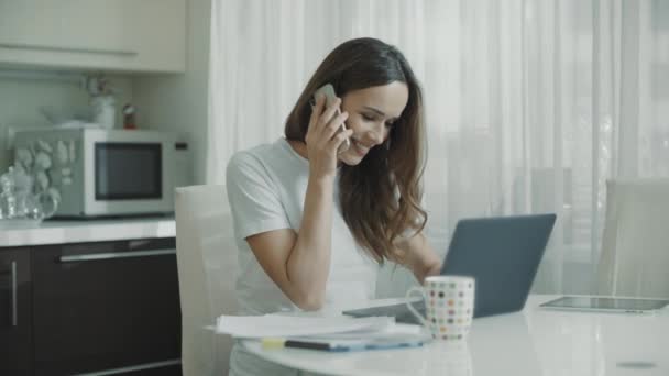 Jonge vrouw belt thuis de keuken. Zakelijke vrouw aan het praten mobiele telefoon — Stockvideo