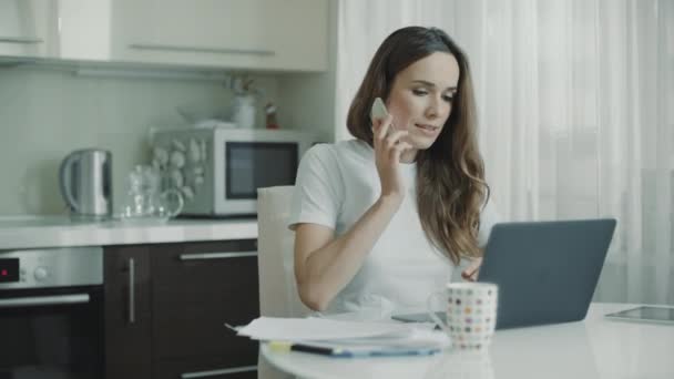 Trieste vrouw met behulp van telefoon thuis werkplek. Boos vrouw praten mobiele telefoon — Stockvideo