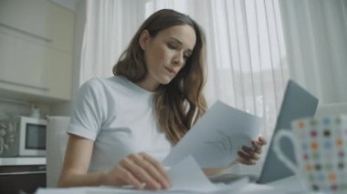 Evde belgelerle çalışan düşünceli bir kadın. Endişeli iş kadını