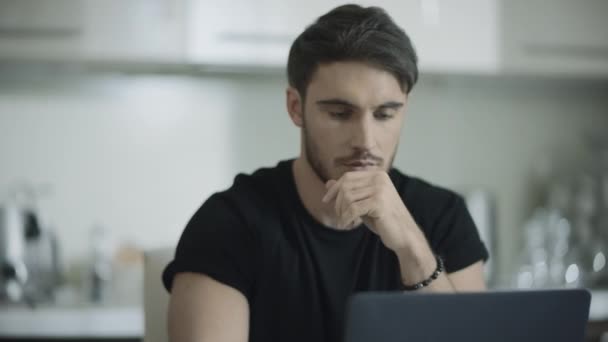 Un hombre serio trabaja en el portátil. Un tipo mirando un monitor de computadora. Hombre usando cuaderno — Vídeos de Stock