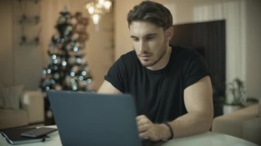 Noel tatilinde evde dizüstü bilgisayar kullanan erkek. Bilgisayarda çalışan adam