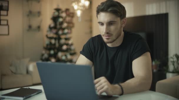 Happy man working on laptop computer at christmas. Smiling guy looking computer — Stock Video