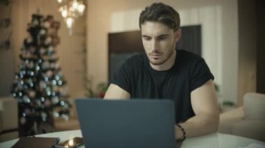 Noel evinde telefon konuşan ciddi bir adam. Bilgisayar masasında çalışan erkek adam