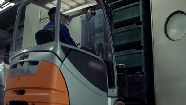 Man arbetar på elektriska gaffeltruck tar bort lådor från hyllor i lager — Stockvideo