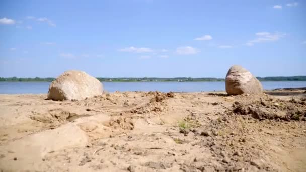 Sabbia e pietre enormi su riva di lago vicino a villaggio. Farfalle volare vicino al lago — Video Stock