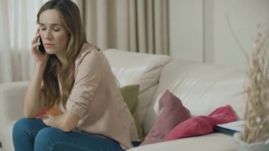Üzgün kadın ev kanepede telefon konuşuyor. Cep telefonu kullanan depresif müşteri
