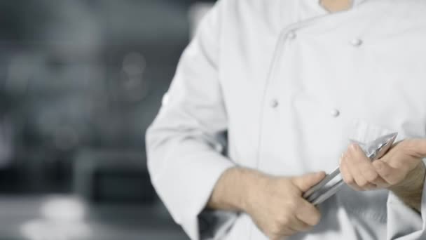 Chef con pinzas metálicas en cocina profesional. Primeros planos manos masculinas con pinzas . — Vídeos de Stock