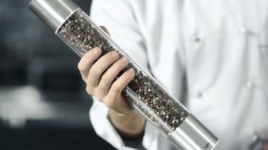 Erkek şef mutfakta biber kutusuyla yemek pişirir. Closeup adam eller pepperbox ile oynamak.