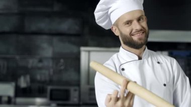 Mutfakta silindirle poz veren şef adam. Silindir pimile oynayan gülümseyen şef