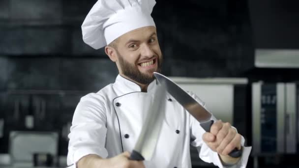 Ο σεφ ποζάρει με μαχαίρια στην κουζίνα. Σεφ άνθρωπος που διασκεδάζει με τα εργαλεία στην κουζίνα. — Αρχείο Βίντεο