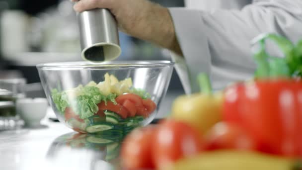 Küchenchef würzt Salat im Restaurant. Nahaufnahme Hände pfeffern Gemüse. — Stockvideo
