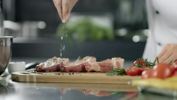 Chef di sesso maschile che insalina carne in cucina. Primo piano chef mani salatura bistecca sul posto di lavoro — Video Stock