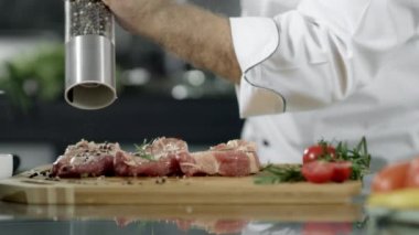 Erkek şef mutfakta et içiyor. Closeup şef eller biber biftek