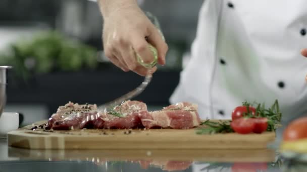 Chef cocinando bistec crudo en el restaurante de cocina. Chef engrasando filete de cerdo — Vídeos de Stock