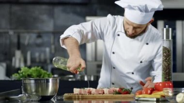 Şef profesyonel mutfakta et pişiriyor. Şefin çiğ biftek pişirme portresi.