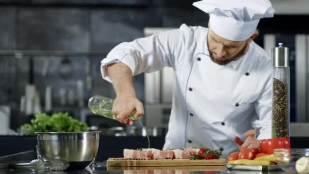 Koch kocht Fleisch in professioneller Küche. Porträt des Chefs, der rohes Steak kocht. — Stockvideo