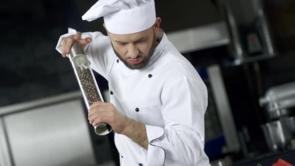 Retrato de chef cocinando en la cocina. Primer plano chef salpimentando comida en cámara lenta — Vídeo de stock