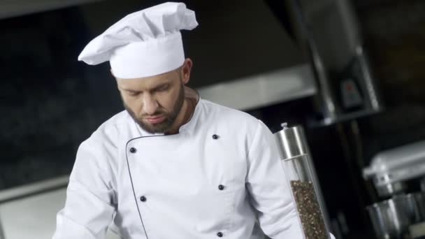 Porträt eines Küchenchefs, der Essen in der Küche salzt. Konzentrierter Koch kocht Mahlzeit — Stockvideo