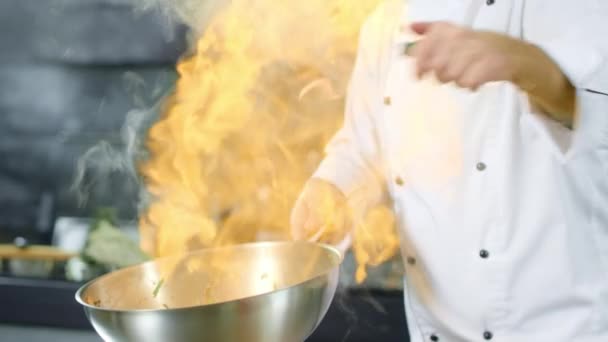Chef főzés élelmiszer tűz láng serpenyőben a konyhában. Chef kezek ételkészítés