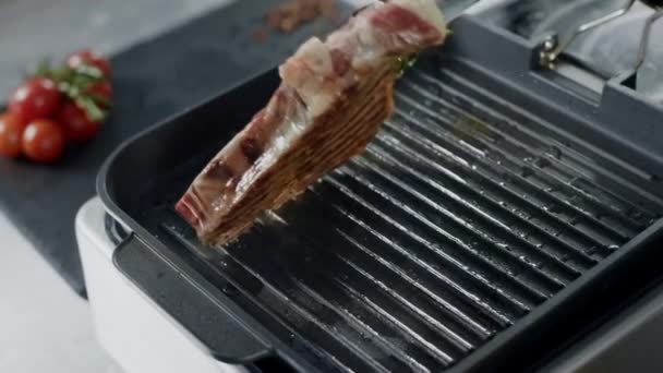 Szef kuchni przygotowuje mięso na patelni. Zbliżenie człowiek ręce toczenia stek z szczypce. — Wideo stockowe